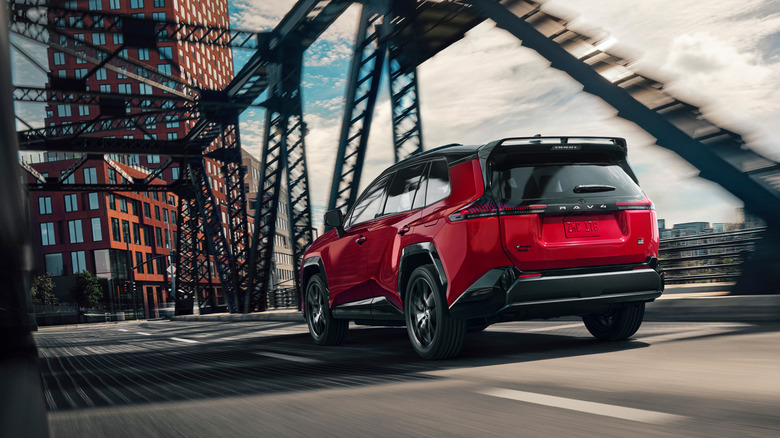 Rear 3/4 view of red Toyota RAV4 GR Sport driving on bridge.
