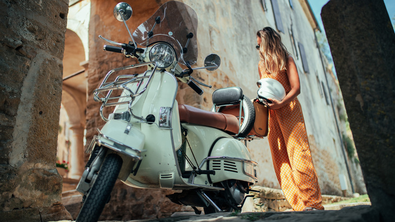 A woman with her parked Vespa.