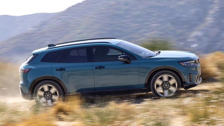 A blue Honda Prologue driving on a city street, front 3/4 view