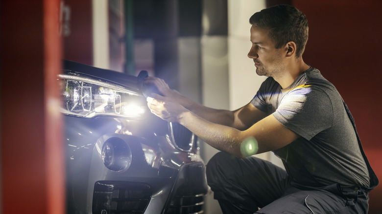 Una persona que pule los faros brillantes en un SUV BMW.