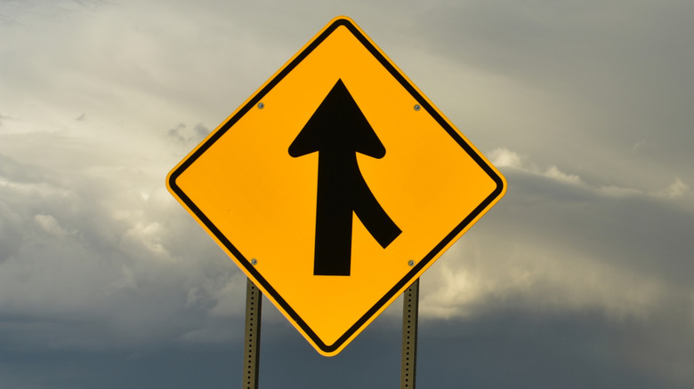 Merge lane sign on road while it's overcast
