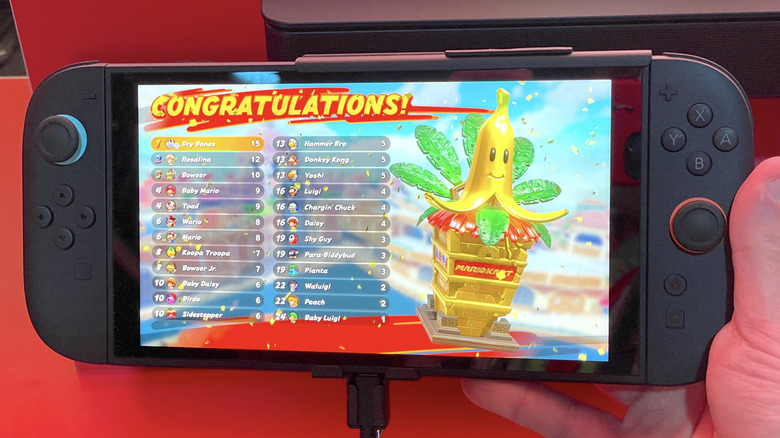 Hand holding a Switch 2 displaying a Mario Kart World race results screen.