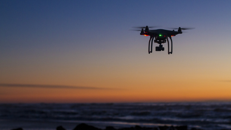 A drone flies over the sea at sunset