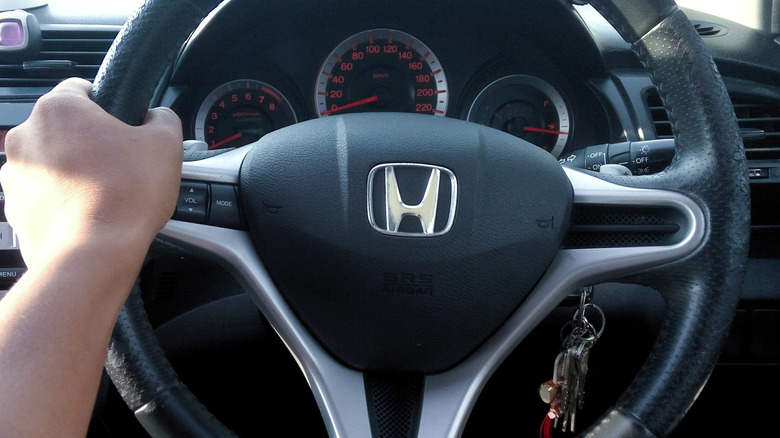 View of a hand holding a Honda steering wheel