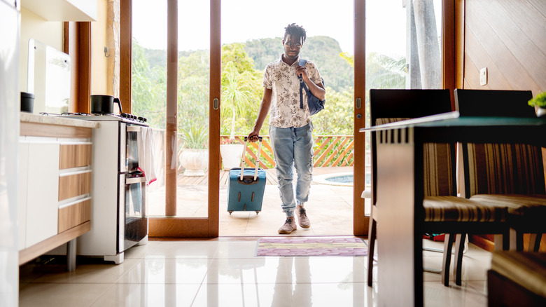 man entering room with rolling luggage