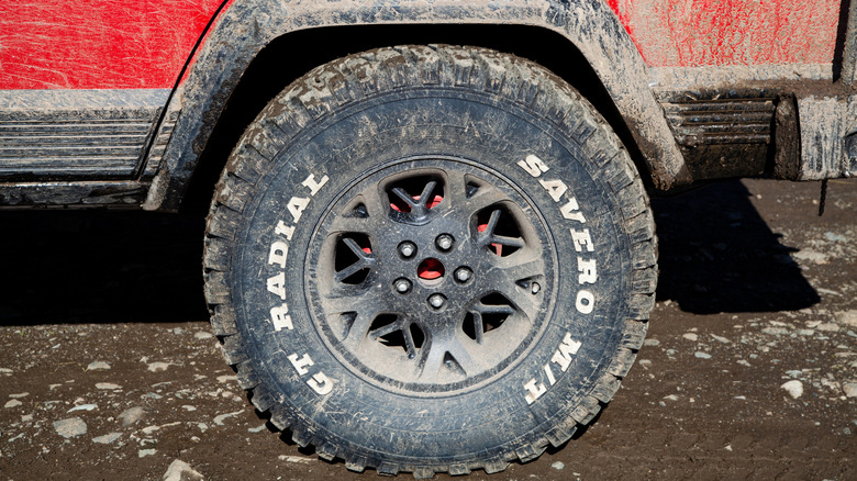 A close up of a red truck with M/T labeled tires