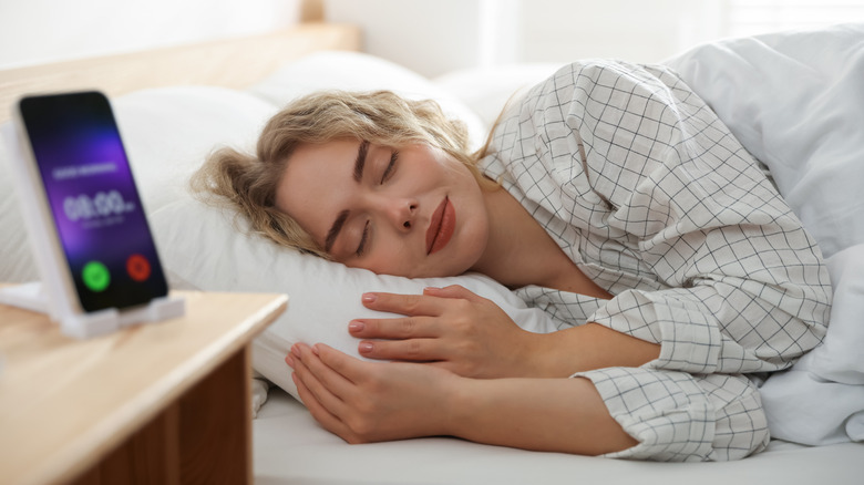 A sleeping person being woken by a smartphone alarm