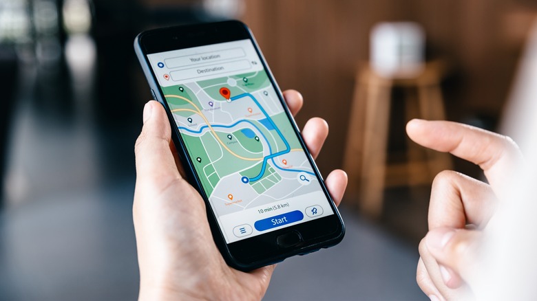 Smartphone displaying navigation app, held in hand