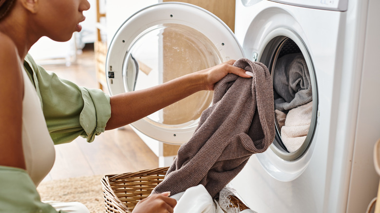 Putting clothes inside a dryer.