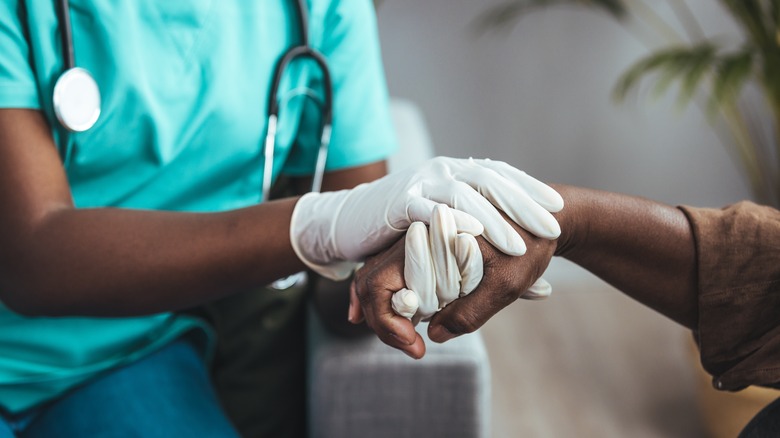 Healthcare employee holding patient's hand