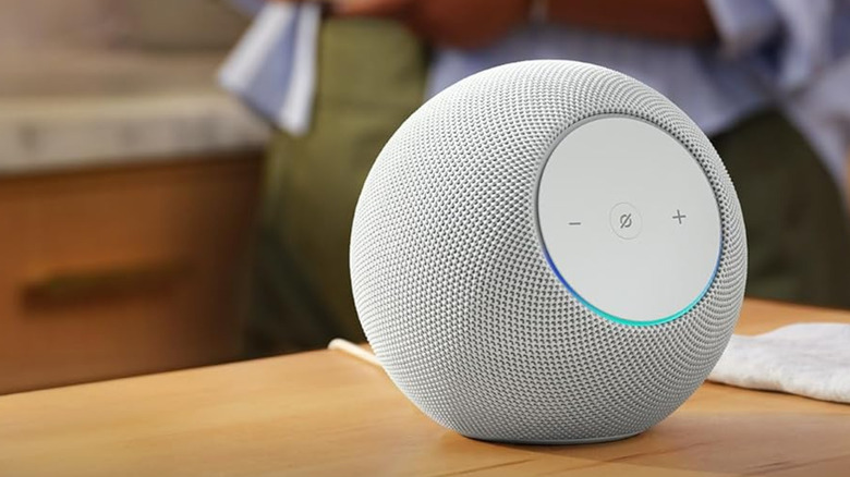 An Amazon Echo Studio on a table, a person in the background.