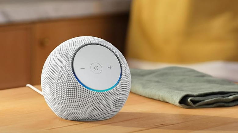 An Amazon Echo Dot on a table near a rag.