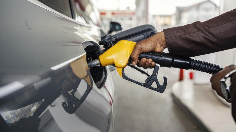 A person putting a gas pump nozzle into a car.