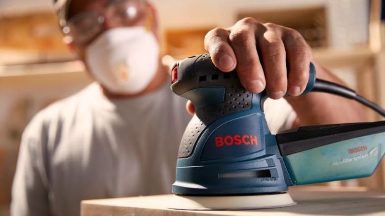 Person using Bosch ROS20VSC Palm Sander on table