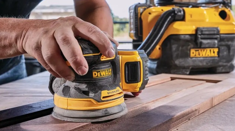 Person sanding board with a DeWalt 20V Max Random Orbital Sander