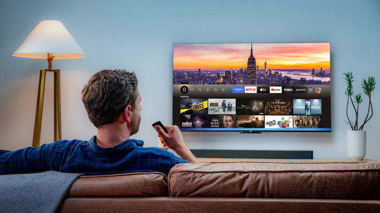 Man watching Fire TV-enabled device with Amazon Alexa remote