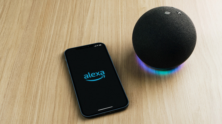 Amazon Alexa depicted on a phone next to an Echo smart speaker