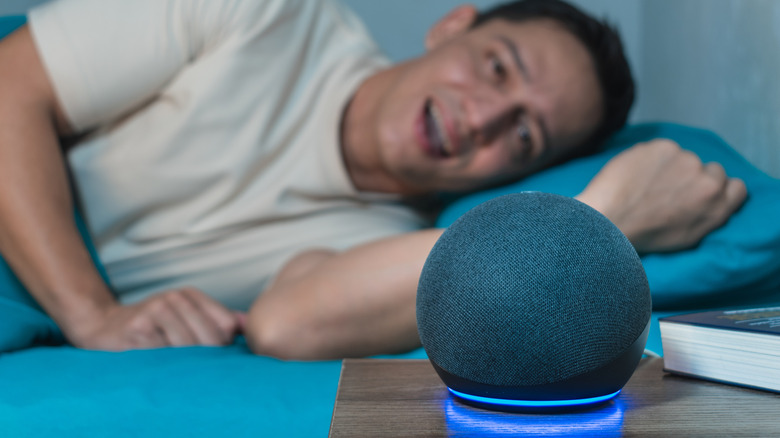 A person in bed talking to Alexa on an Echo speaker