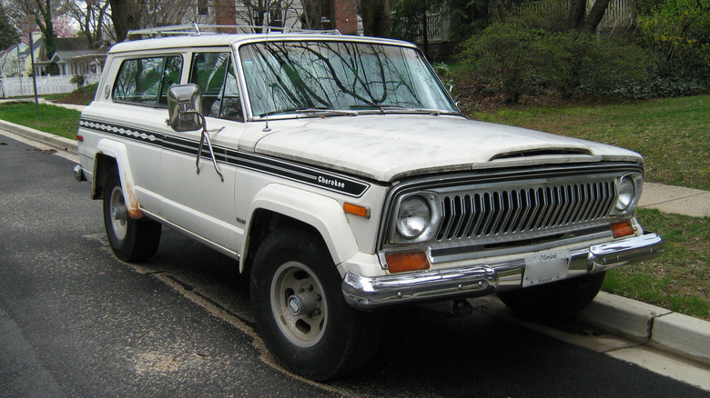 A white Jeep Cherokee SJ with slight surface rust on the rear fenders, front 3/4 view