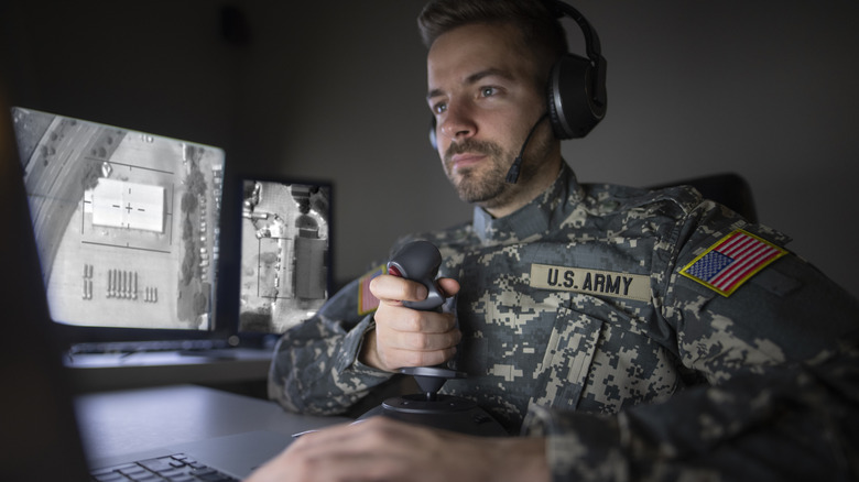 U.S. Army soldier in a command center controlling a drone using a joystick.