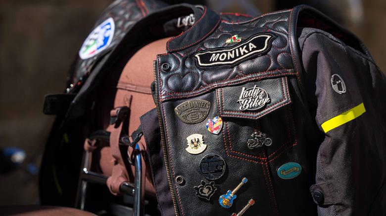 A leather biker jacket festooned with various patches and badges.