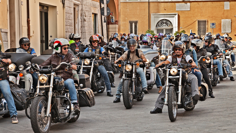 Several riders in full gear on their way out of a narrow street on a ride