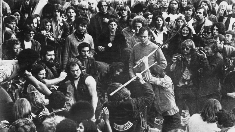 Fans look on as a member of the Hells Angels beats a concert goer with a pool cue at Altamont in 1969