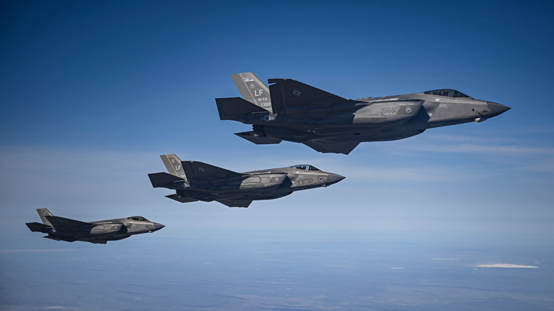 A group of F-35 jets against a blue sky.