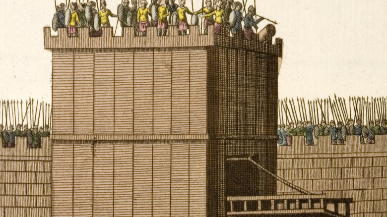 Image of a siege tower approacing fortifications.