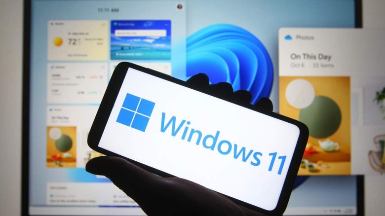Windows 11 logo on smartphone in front of larger screen
