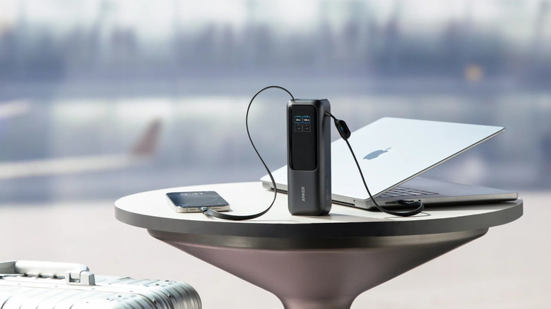 An iPhone and a MacBook on a table getting charged with an Anker Laptop charger