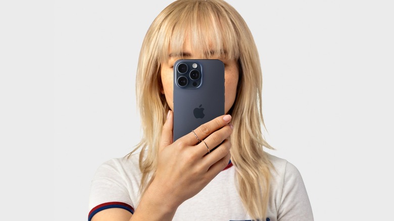 Woman hiding face while holding black iPhone