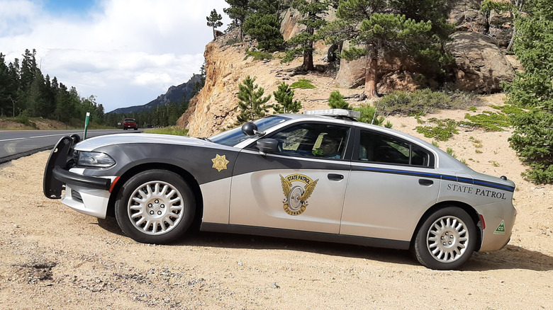 Colorado State Patrol vehicle parked on dirt at the side of a highway.