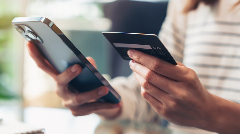 woman holding iPhone and credit card