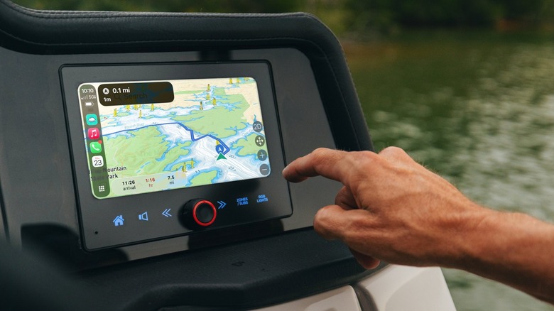 Hand reaching out to a boat helm display running Savvy Navvy through Apple CarPlay.