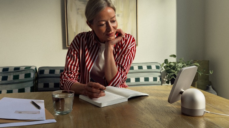 Woman reads from Apple HomeView device on table.