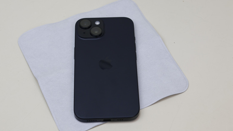 A black iPhone 15 on top of the Apple polishing cloth