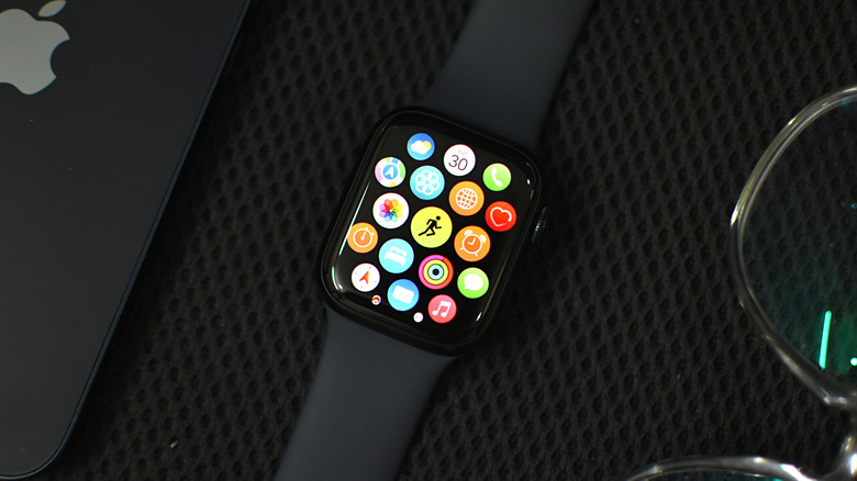 Apple Watch on a black textured surface on with an iPhone