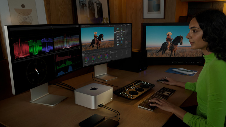 Woman working at computer desk with three monitors