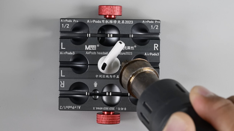 A technician heating an AirPods 4 earbud after clamping it into a jig