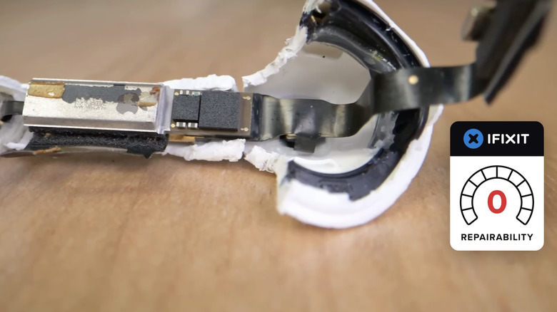 A torn-down AirPods 4 earbud on a table with an iFixit repairability score next to it