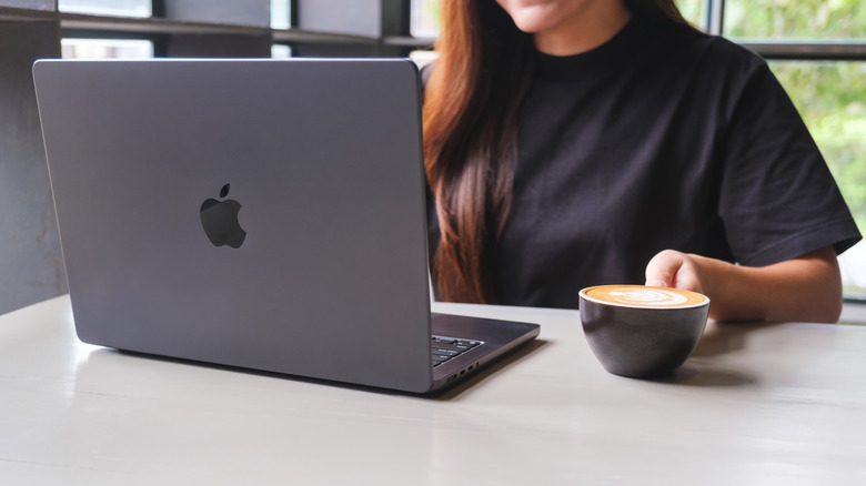 Person using a MacBook Pro at a cafe