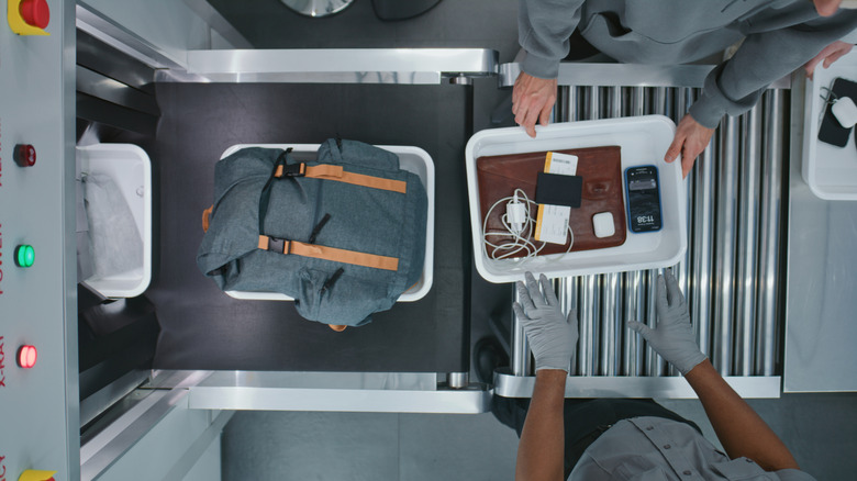 Looking down on a TSA checkpoint with electronic devices in a tray