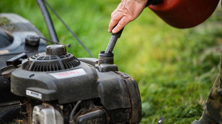 Refueling gasoline lawn mower before mowing grass