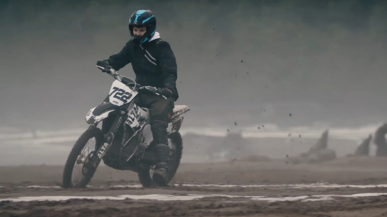 A rider riding an Alta dirt bike on some mud