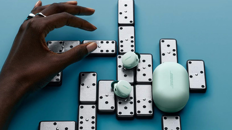 A pair of dewdrop mint Bose QuietComfort Earbuds on a set of dominoes.