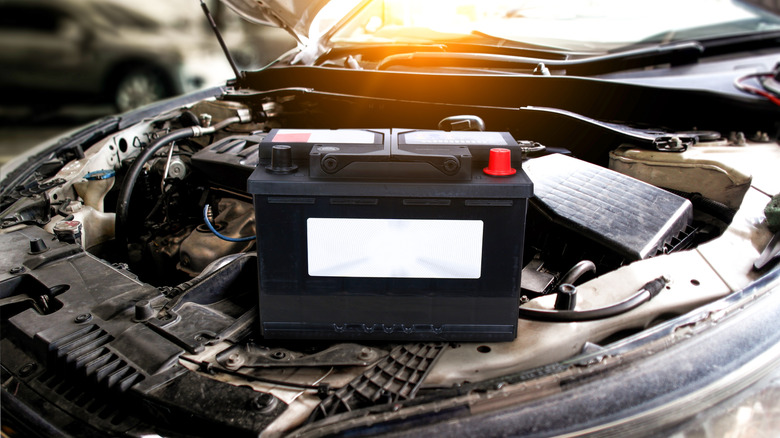 Car battery sitting on a car with the hood open