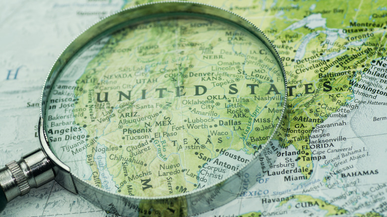 A magnifying glass placed over a green map of the United States