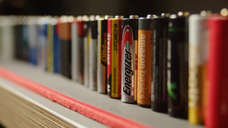 Many different AA batteries lined up on a shelf