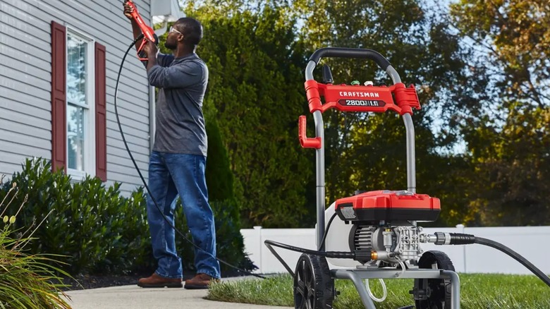 A person using a Craftsman pressure washer on a house.